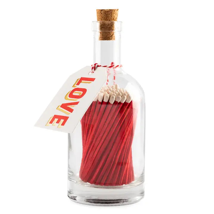 Glass bottle with red matches and a 'LOVE' tag on a white background