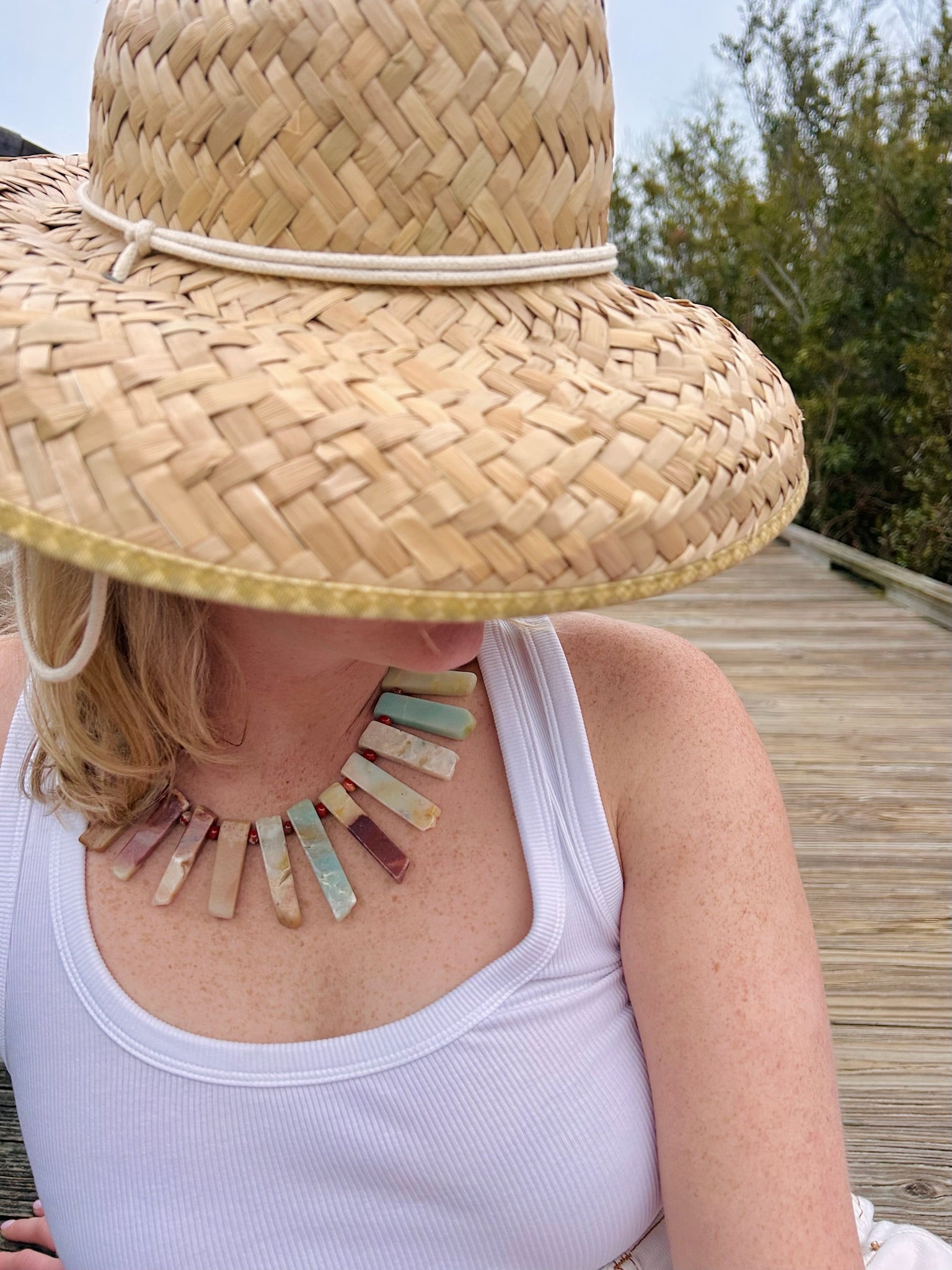Person wearing a straw hat and colorful necklace